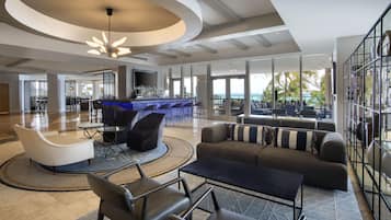 A spacious lobby with a bar area, seating arrangements, and large windows offering a view of the outdoors.