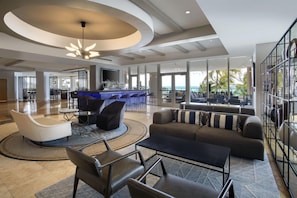 A spacious lobby with a bar area, seating arrangements, and large windows offering a view of the outdoors. - DoubleTree Resort & Spa by Hilton Ocean Point-N. Miami Beach (Sunny Isles Beach)