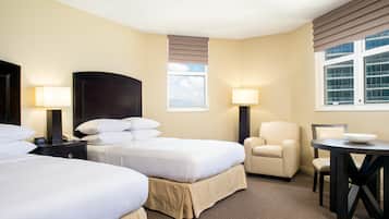 Habitación de hotel con dos camas, un escritorio, una silla y un ventanal.