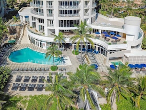 A multi-story hotel with a pool, sun loungers, and palm trees. - DoubleTree Resort & Spa by Hilton Ocean Point-N. Miami Beach (Sunny Isles Beach)