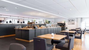 Een modern café met een centraal loket, zwart en houten meubilair en een schoon, licht interieur.
