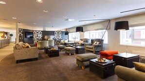 Een moderne woonkamer met banken, poefs, een salontafel en een televisie.