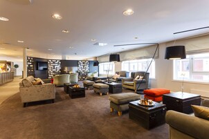 A modern living room with sofas, ottomans, a coffee table, and a TV.