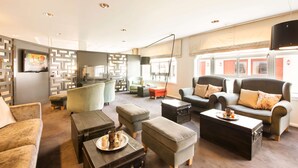 Een moderne woonkamer met banken, poefs, een salontafel en een televisie.