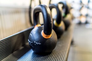 Une rangée de kettlebells noirs avec des touches orange, disposés sur un support.