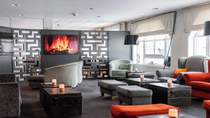 Een moderne woonkamer met een open haard, comfortabele zitplaatsen en een televisie.