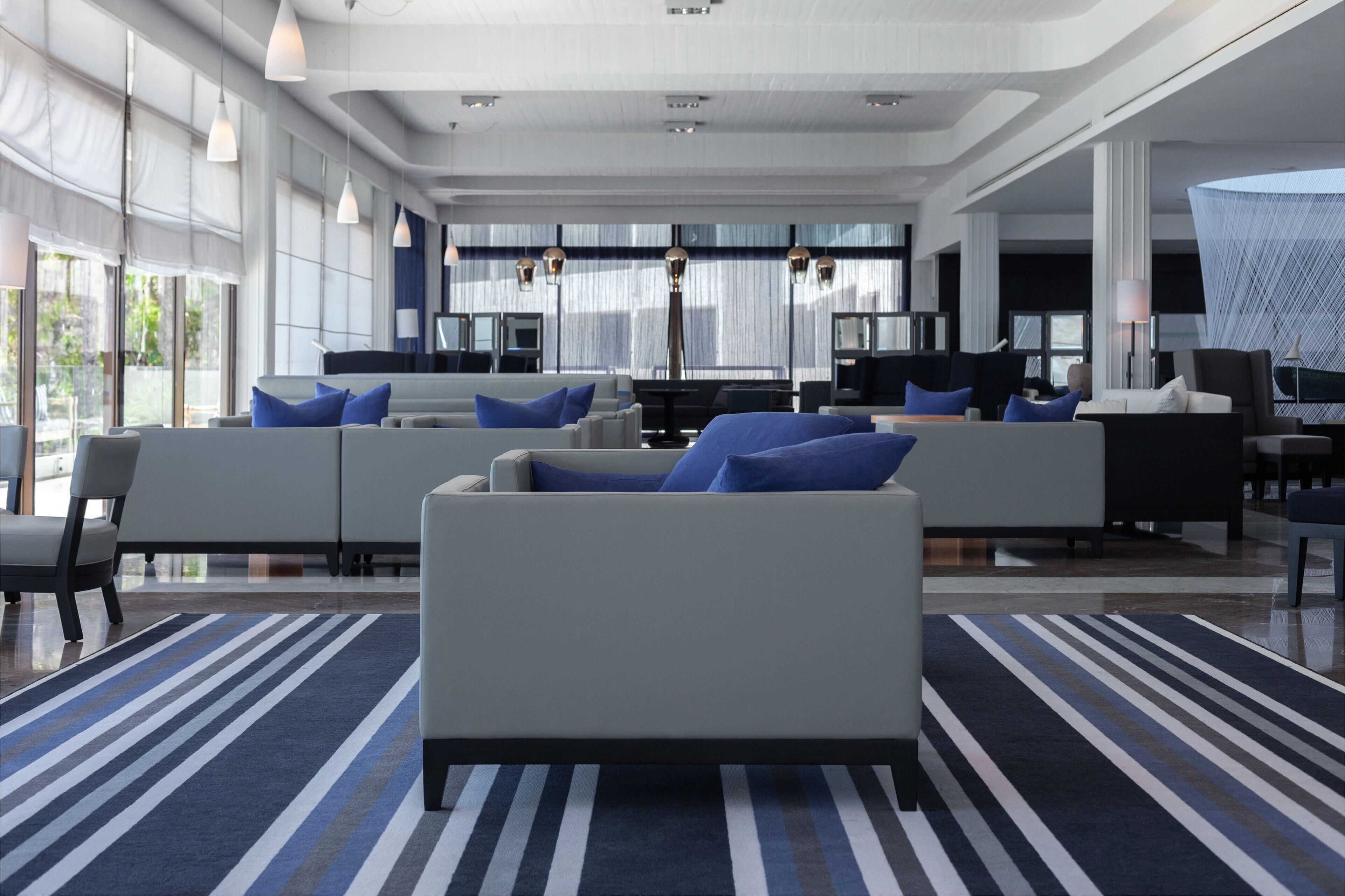 A modern hotel lobby with a spacious seating area, large windows, and contemporary lighting.