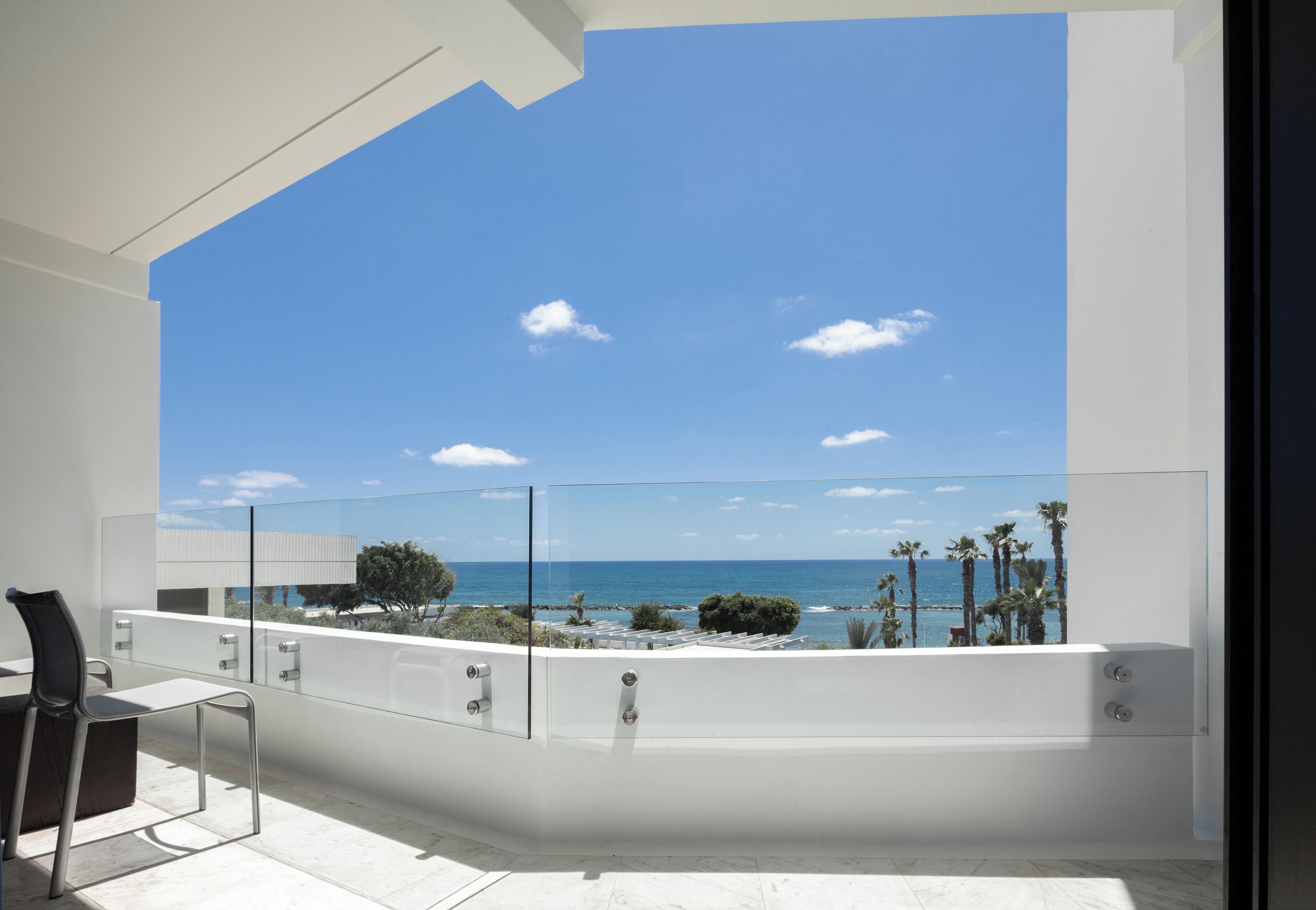 Ein Balkon mit freiem Blick auf das Meer und Palmen.