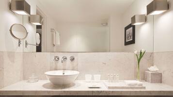 A modern bathroom with a large round mirror, a vessel sink, and two wall-mounted lights.