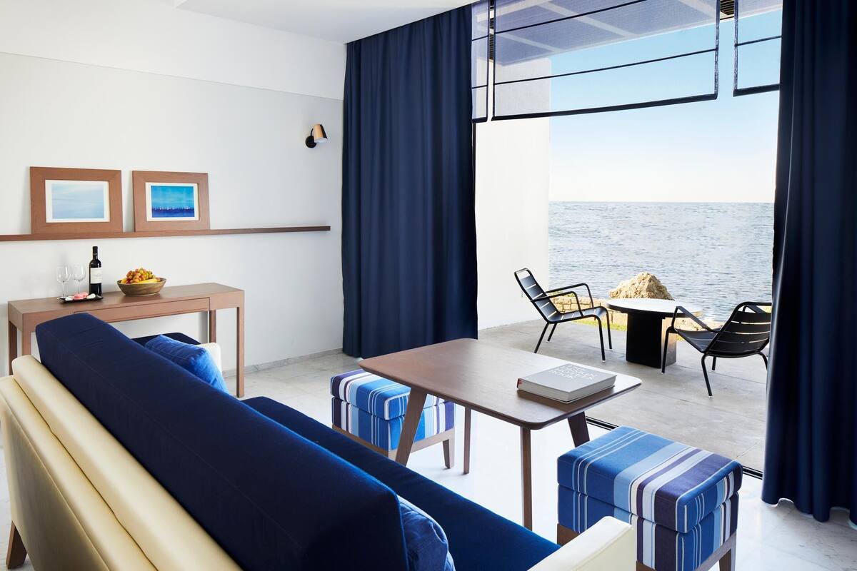 A modern room with a sofa, a table, and a view of the sea.