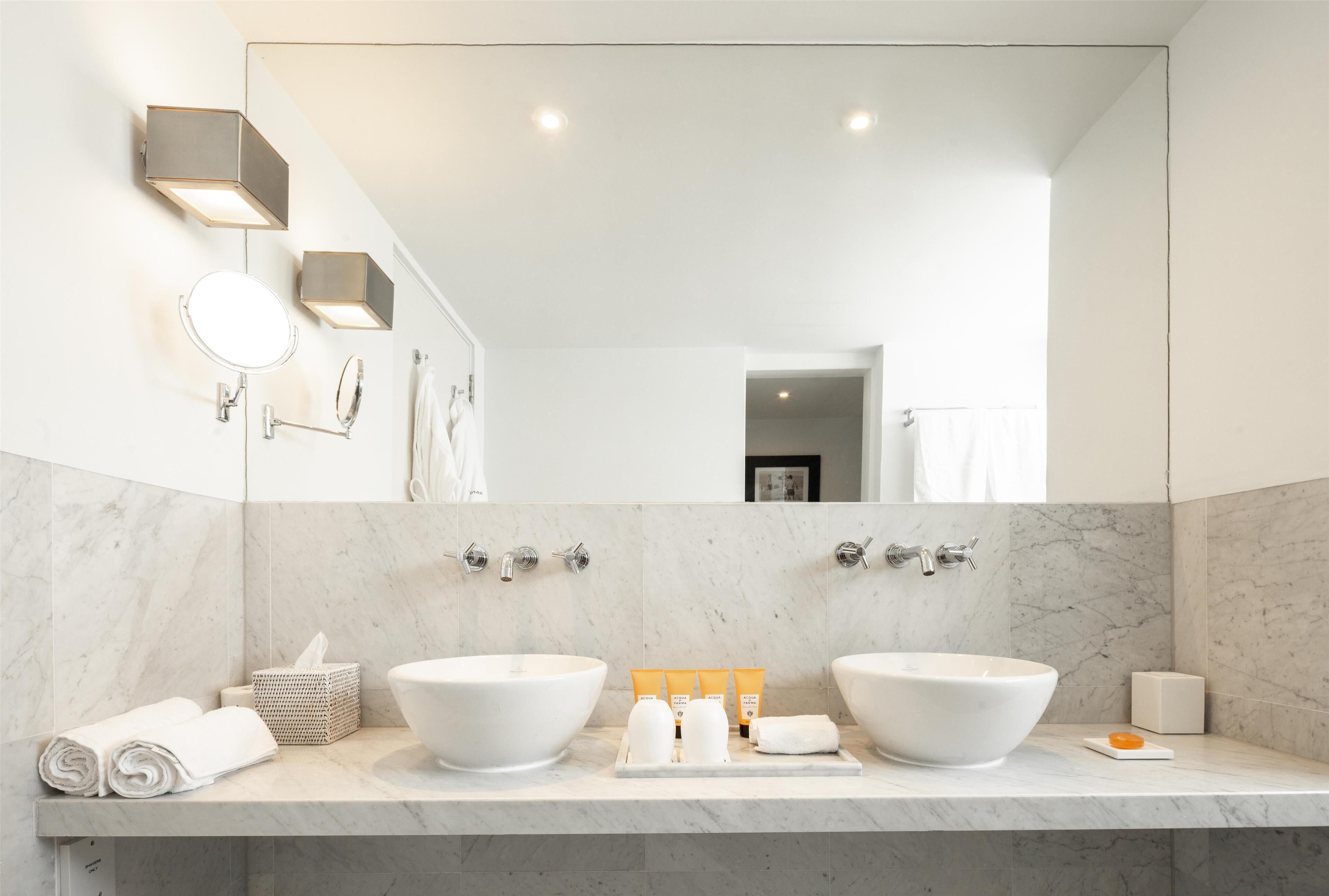 Un baño moderno con dos lavamanos, un espejo grande y un perchero para toallas.