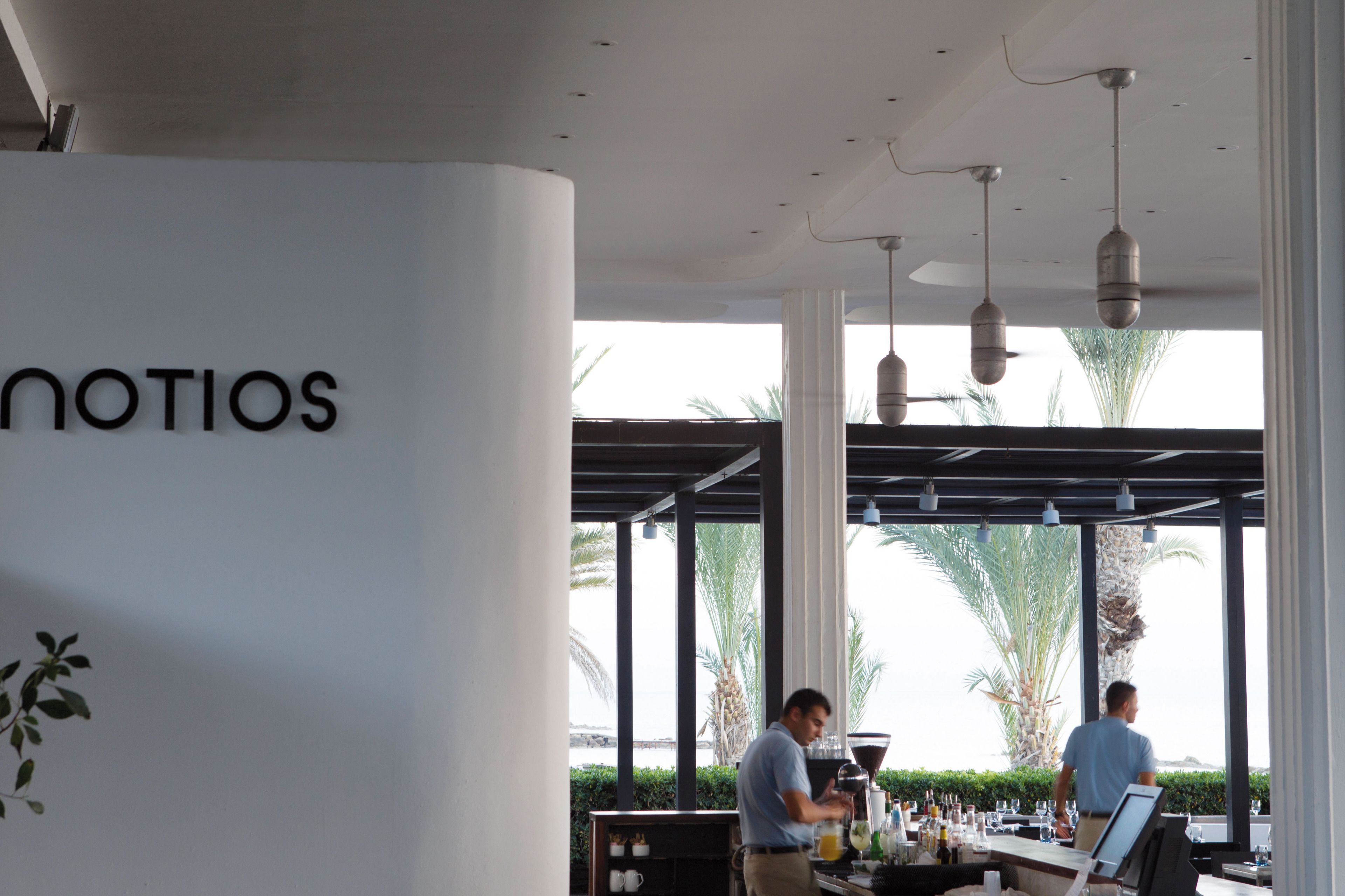 A restaurant with a modern interior, large windows, and a bar area.