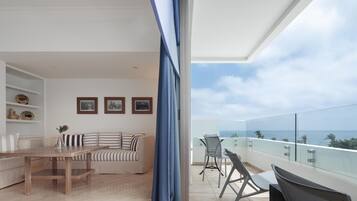 A modern living room with a sofa, a wooden table, and a balcony with a glass railing.