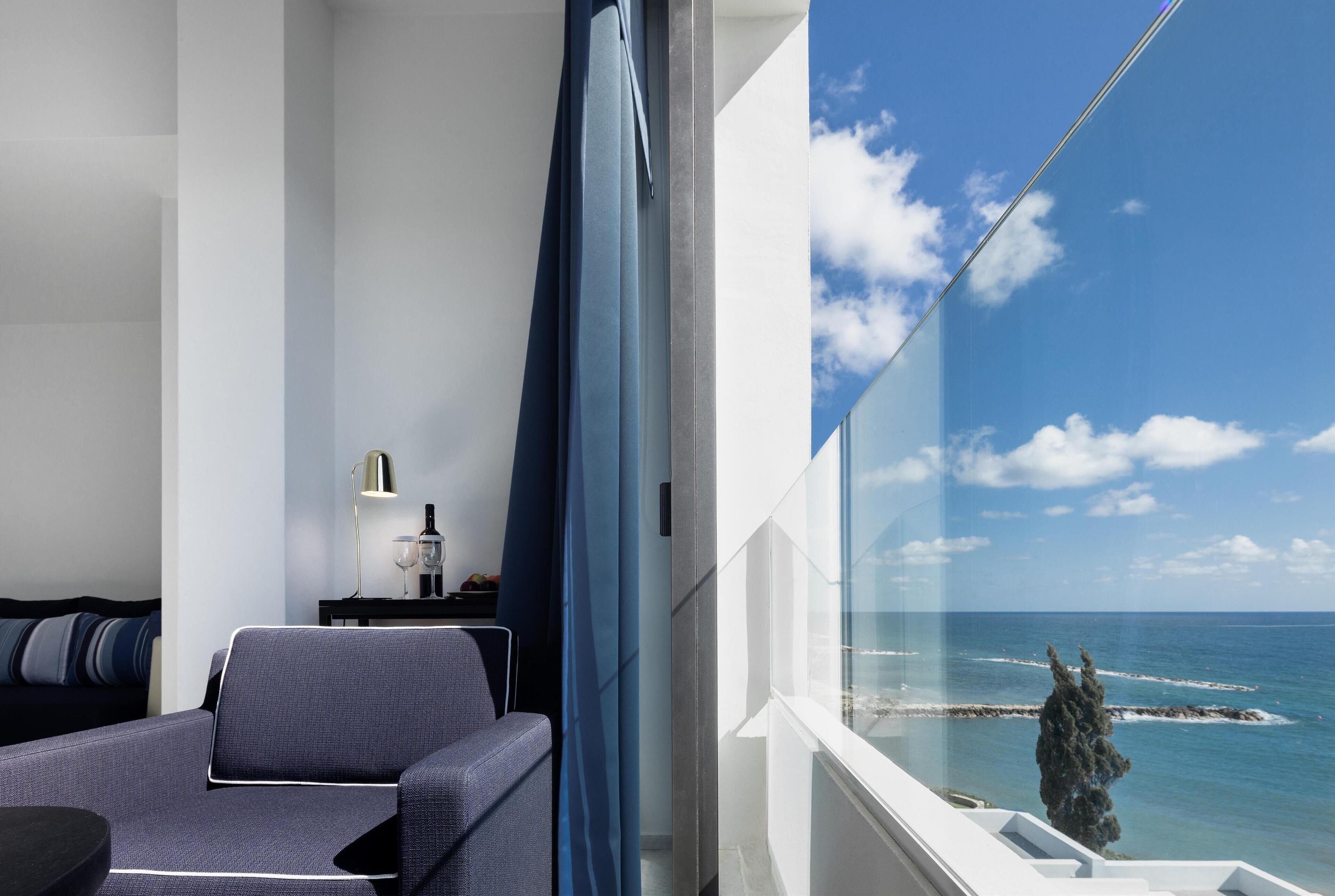A modern hotel room with a balcony overlooking the sea.