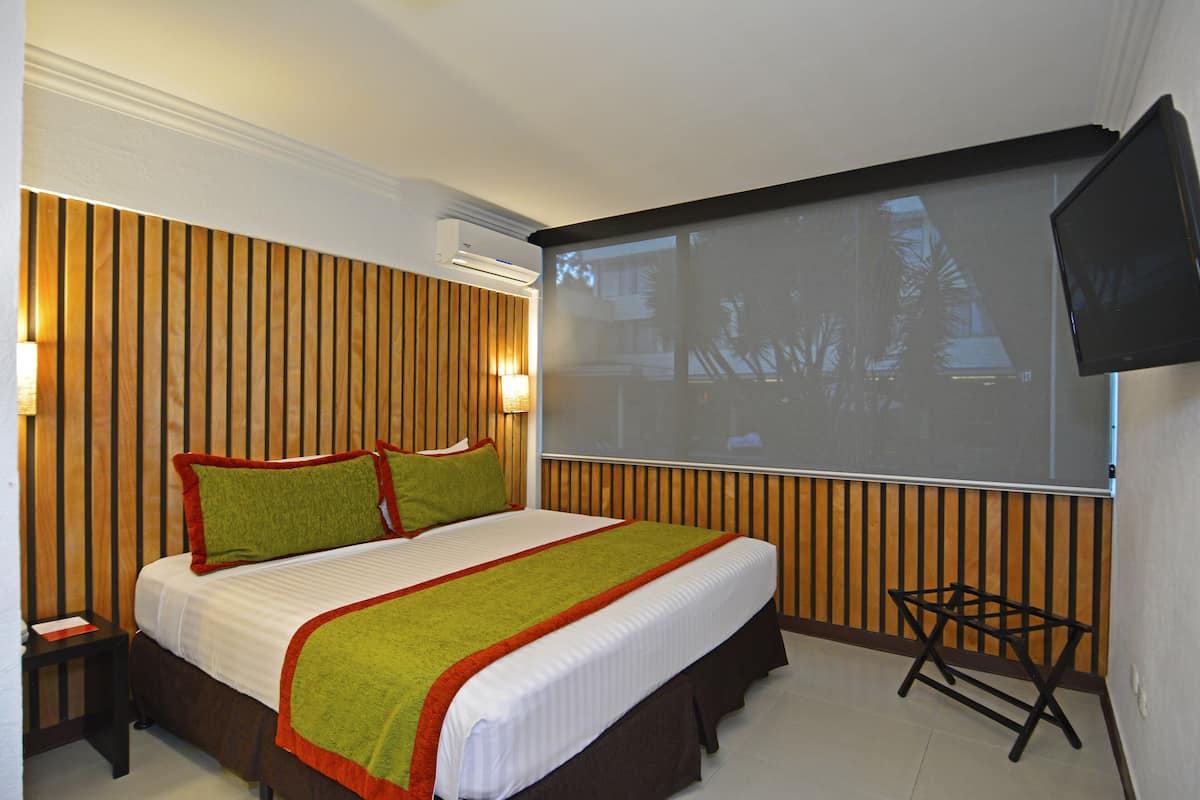 Una habitación de hotel con una cama grande, una pantalla de televisión y un panel de pared de madera.
