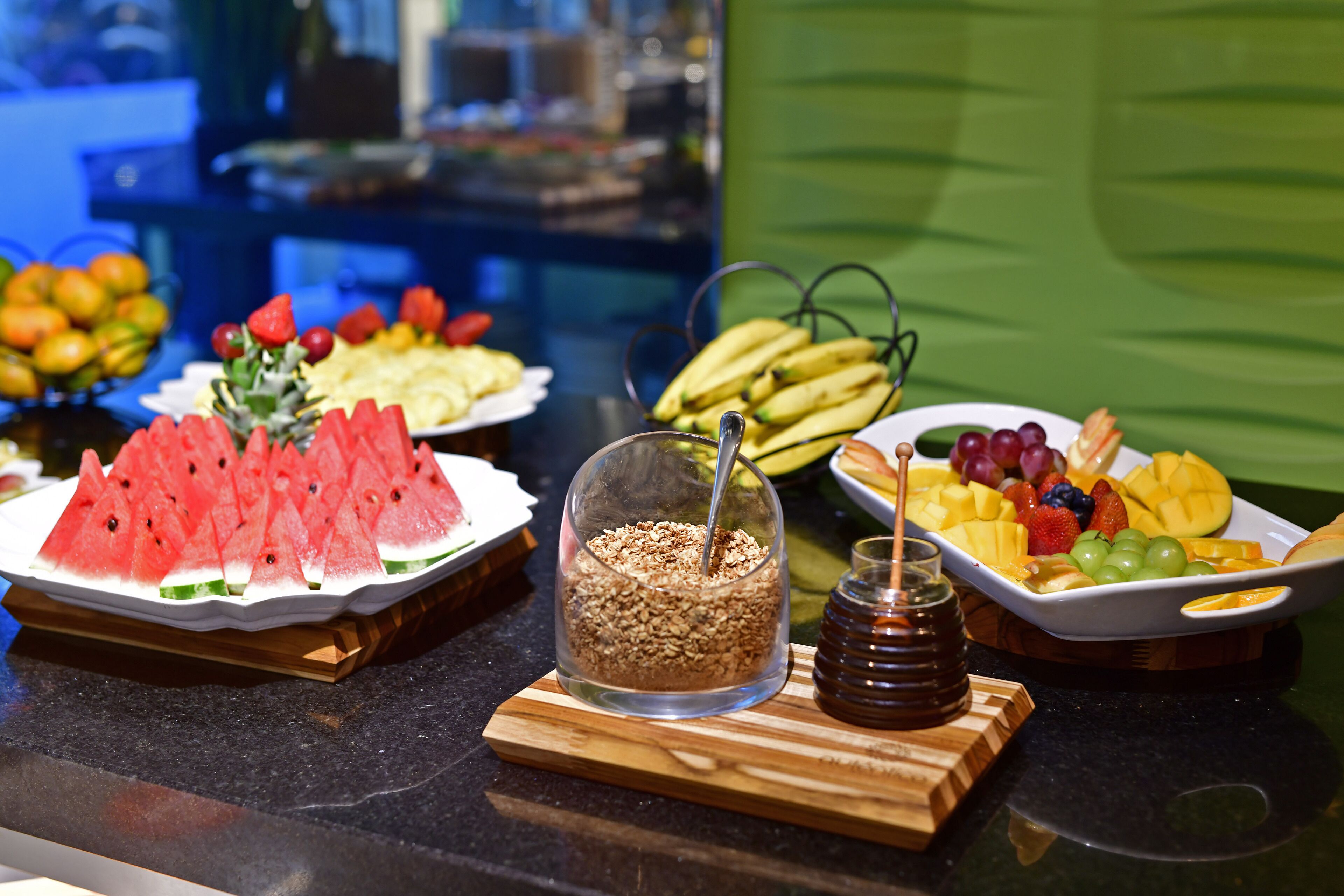 A buffet with various fruits and a honey jar.
