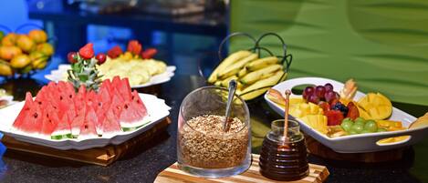 A buffet with various fruits and a honey jar.