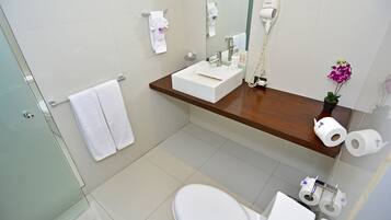 Un baño moderno con un lavabo blanco, cabina de ducha con mampara de cristal y un inodoro.