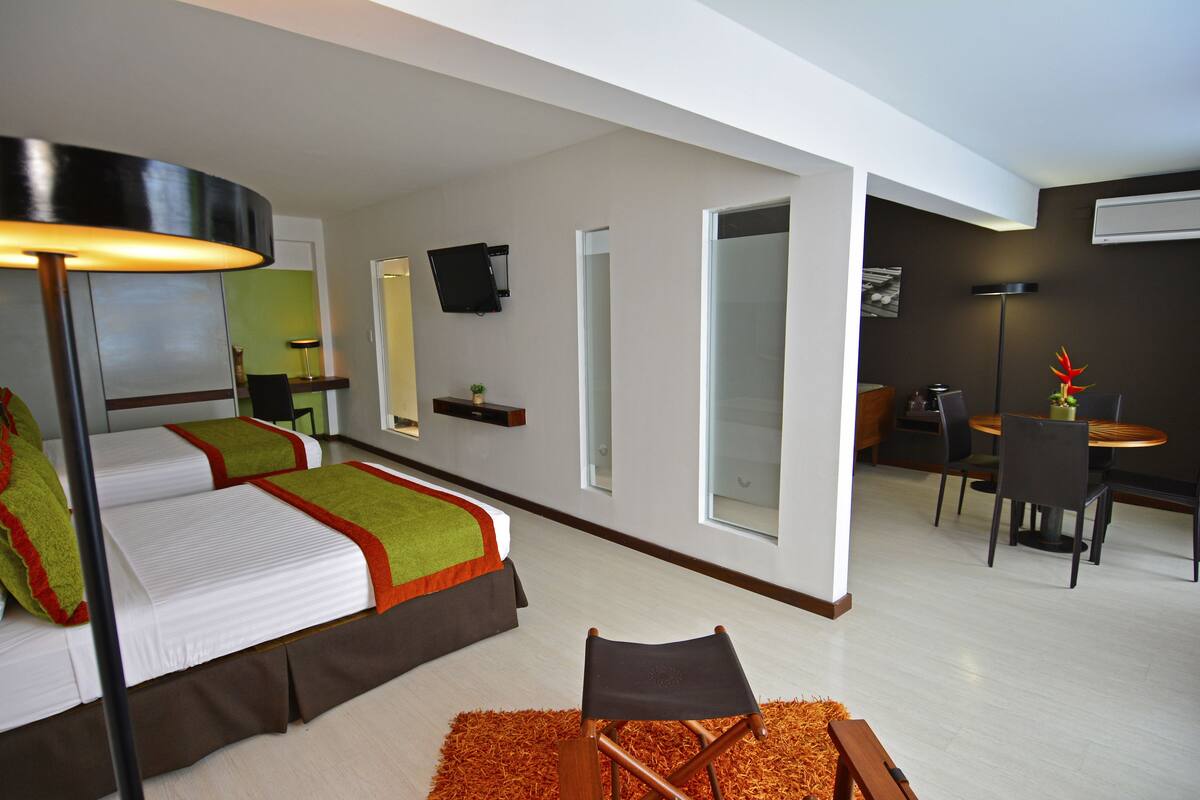Una habitación de hotel moderna con cama, escritorio y zona de comedor.