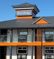 Un edificio con un letrero de Travelodge, balcones y un diseño arquitectónico moderno.