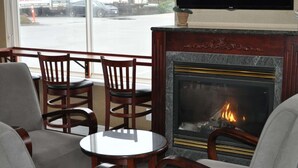 Un rincón acogedor con una chimenea, dos sillas de madera y una mesita.