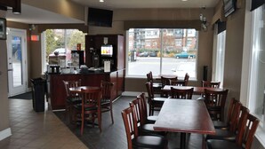 Un interior de restaurante con mostrador, varias mesas y sillas.