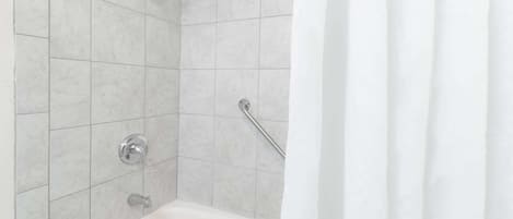 Une salle de bain équipée d’une baignoire, d’une douche et d’une barre d’appui.