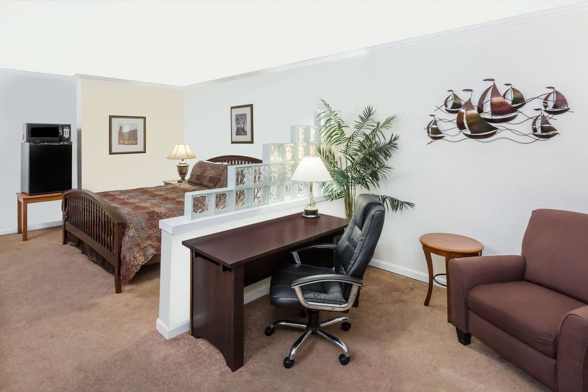 Une chambre à coucher avec un lit, un bureau, un fauteuil de bureau et un canapé marron.
