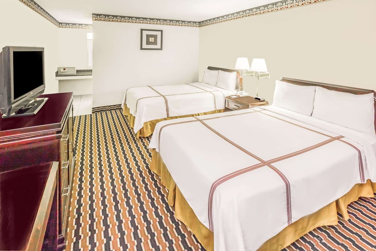 Une chambre d’hôtel avec deux lits, une télévision, un bureau et un sol à motifs.