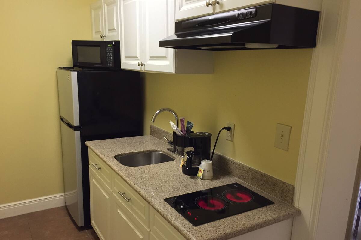 A compact kitchen with a microwave, refrigerator, sink, and stove.