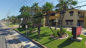 A street view with a 'No Parking' sign, palm trees, and a building with a 'Ramada' sign. - Ramada by Wyndham & Suites South Padre Island At the Beach (South Padre Island)