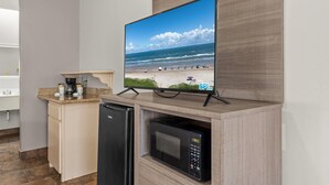 A kitchen with a built-in microwave, a dishwasher, and a flat-screen TV displaying a beach scene. - Ramada by Wyndham & Suites South Padre Island At the Beach (South Padre Island)