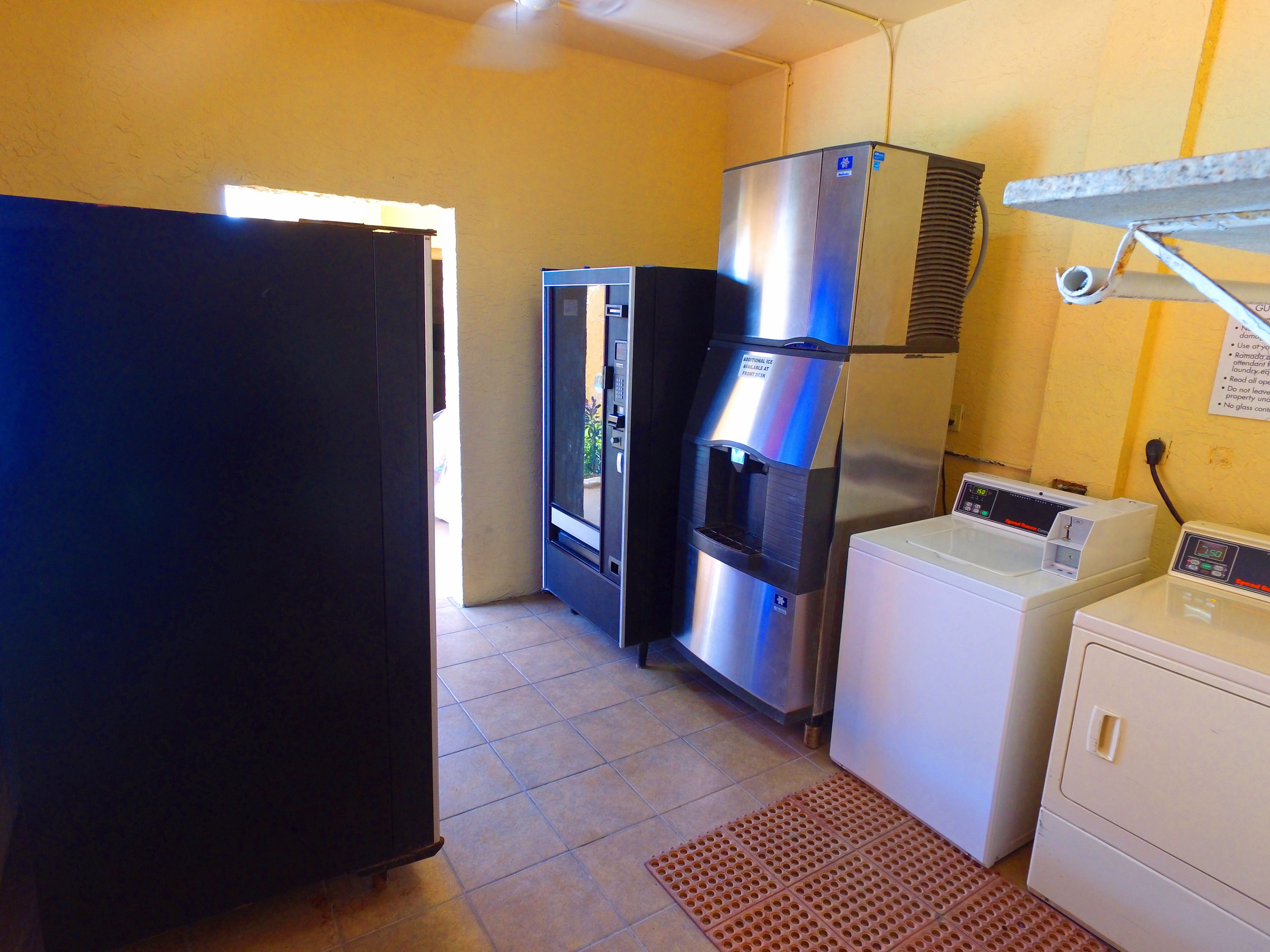 A compact kitchen with a refrigerator, a water dispenser, a washing machine, and a dryer.
