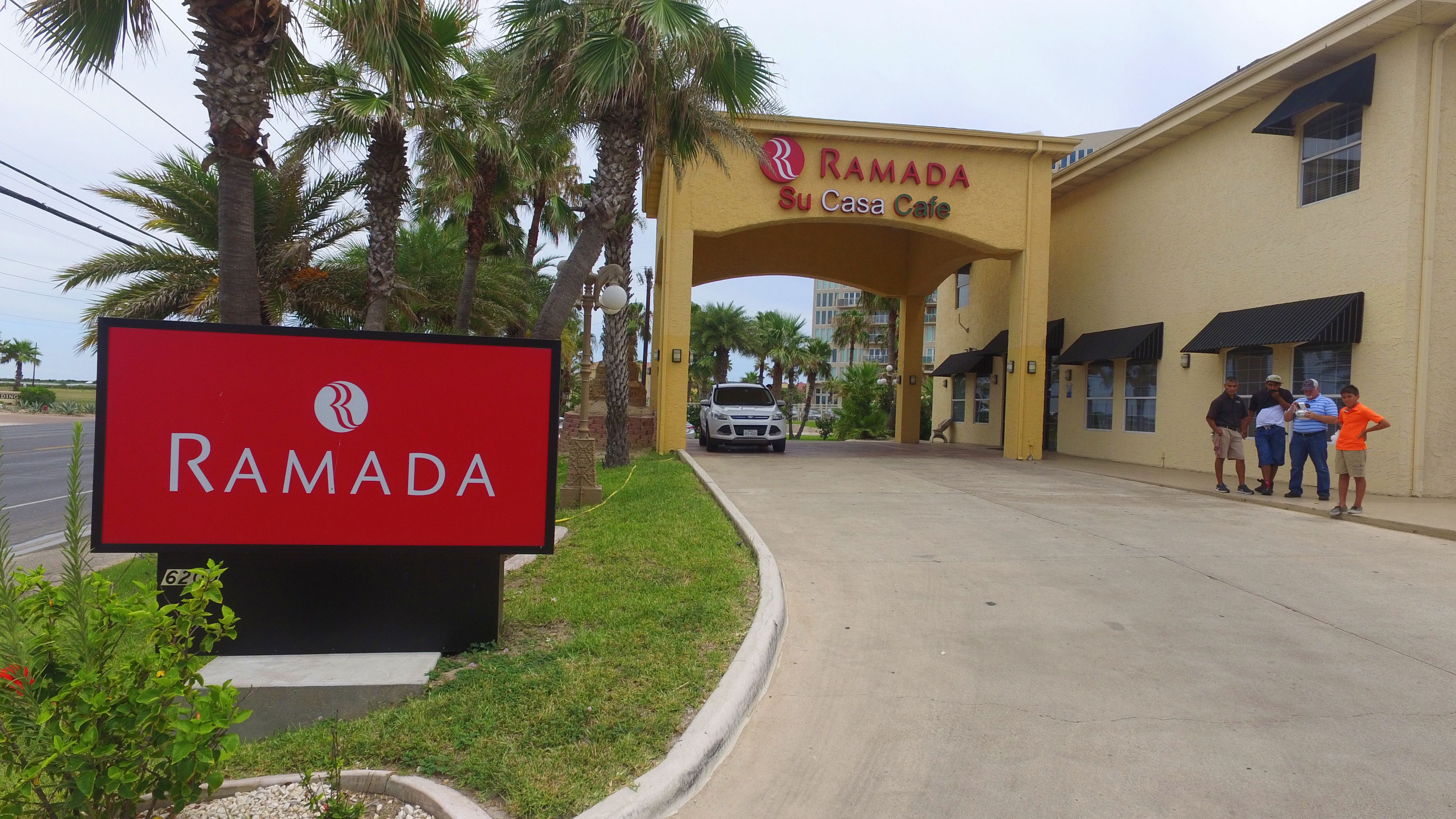 A building with a sign reading "RAMADA Su Casa Cafe" and a red sign with the RAMADA logo.