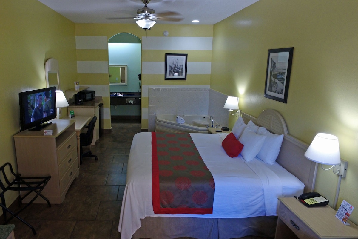 A hotel room with a bed, desk, television, and bathroom.