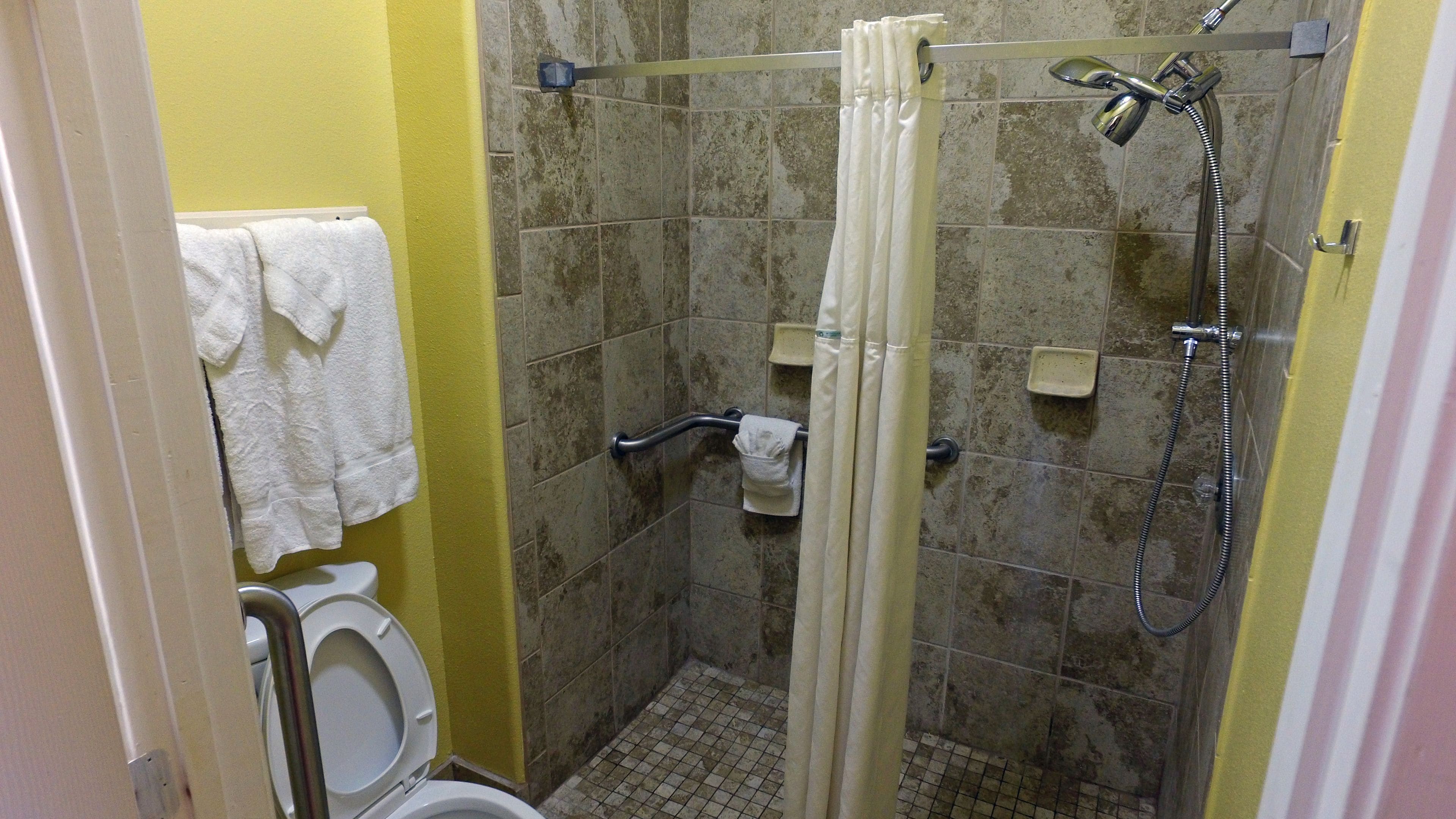 Un bagno piccolo con doccia, WC e porta asciugamani.