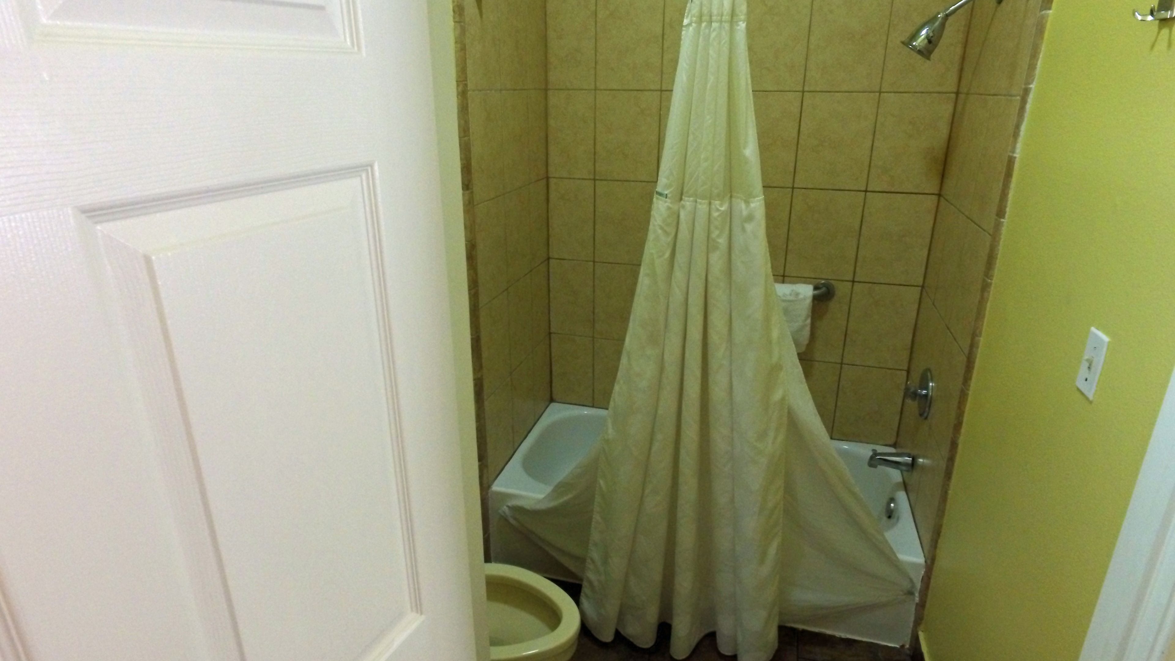 Ein kleines Badezimmer mit Toilette, Dusche und Vorhang.