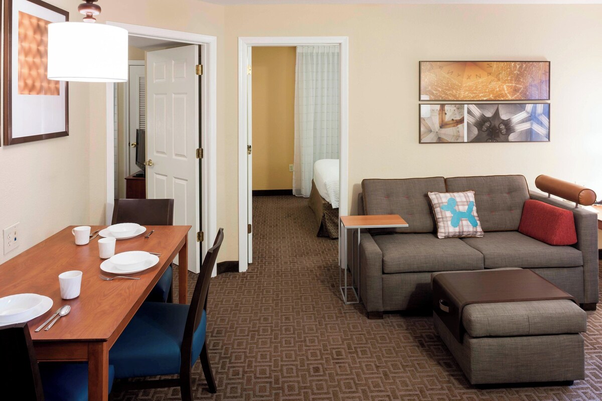 A hotel room with a dining area, a sofa, and a small table.