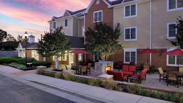 A hotel with outdoor seating, a stone fireplace, and a brick facade.