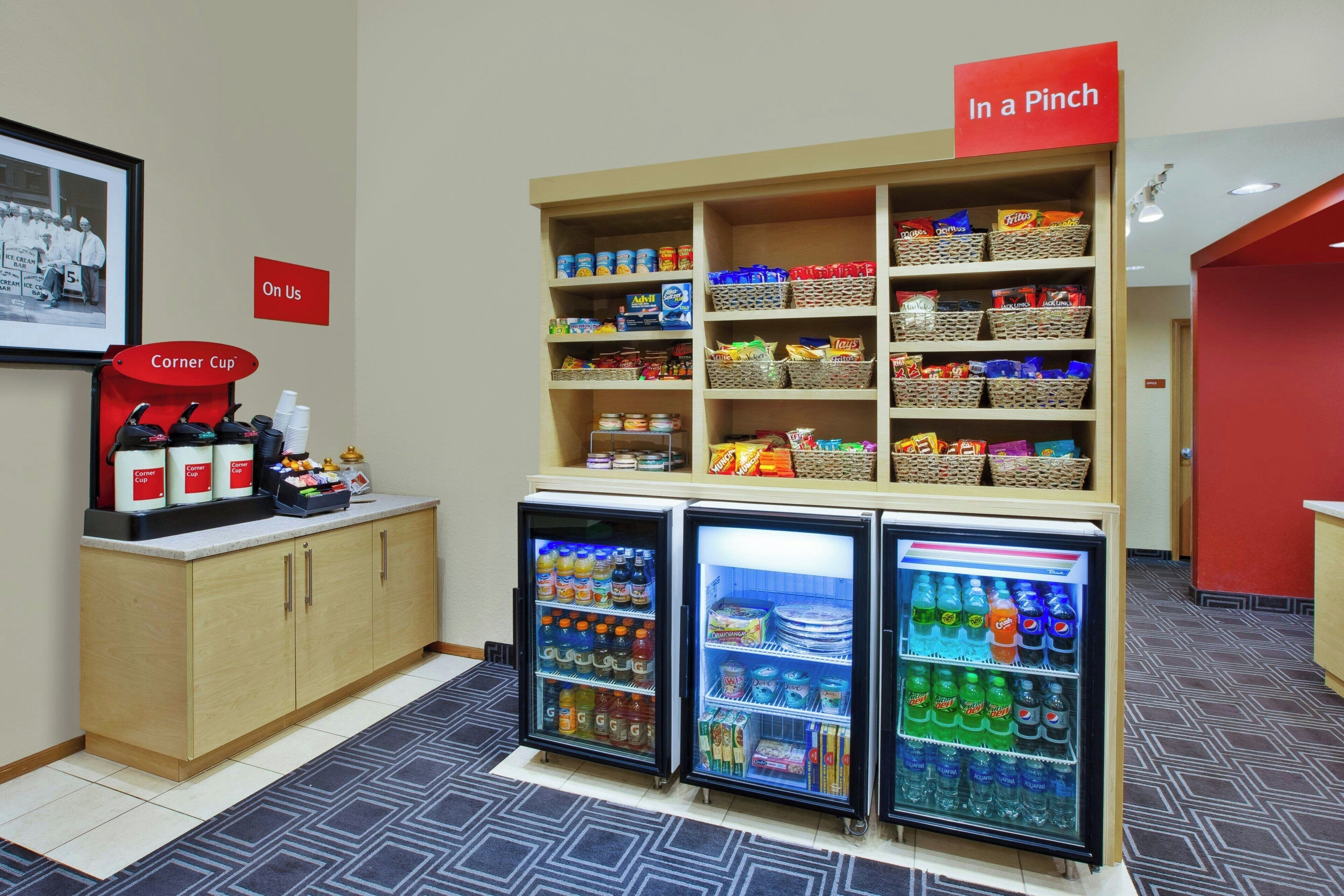 A snack bar with a coffee station, a refrigerator with beverages, and a sign indicating 'In a Pinch' snacks.