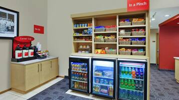 A snack bar with a coffee station, a refrigerator with beverages, and a sign indicating 'In a Pinch' snacks.