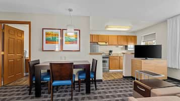 Habitación de hotel compacta con comedor, kitchenette y televisor.