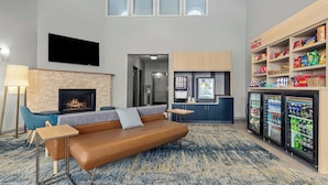 Una sala de estar moderna con sofá, chimenea, televisor de pantalla plana, kitchenette y mini refrigerador con bocadillos.