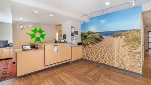 A reception area with a wooden floor, a reception desk, a clock, and a beach mural. - Extended Stay America Suites - Norfolk - Virginia Beach (Virginia Beach)