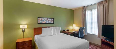 A hotel room with a bed, bedside tables, a desk, a chair, a television, and a window with curtains.