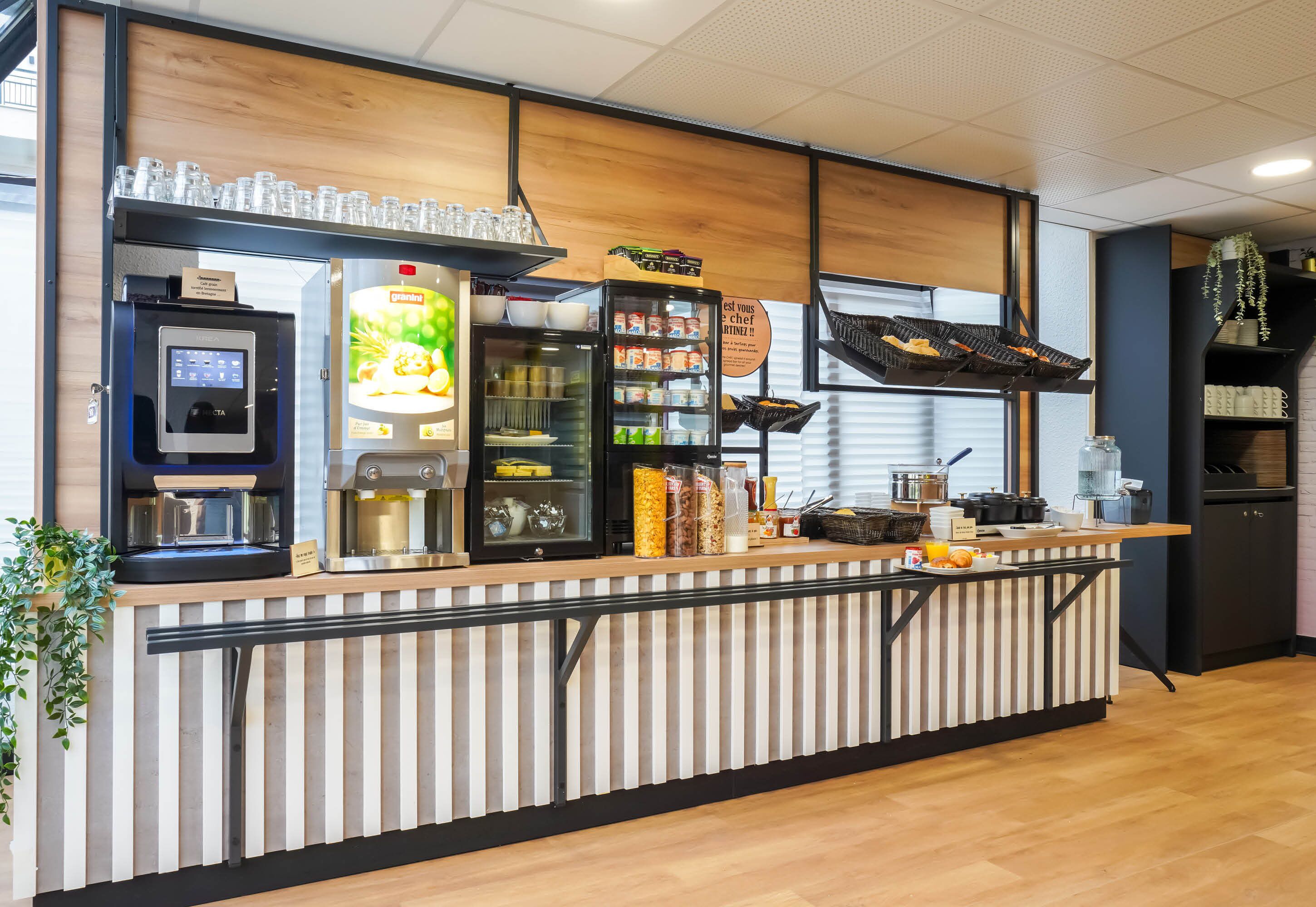 A modern kitchen counter with a coffee machine, a refrigerator, and various food items.