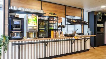 A modern kitchen counter with a coffee machine, a refrigerator, and various food items.