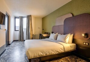 A hotel room with a large bed, a desk, a chair, and a view of the city. - B&B HOTEL Paris Châtillon (Chatillon)