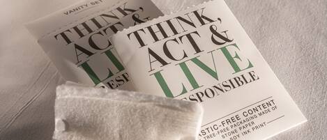 A book titled "Think, Act & Live Responsibly" on a white surface with a black object and a white towel in the background.