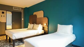 Una habitación de hotel con dos camas individuales, un espejo grande y una pared con textura.